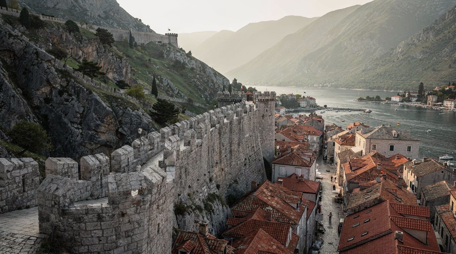 La bahía de Kotor y la muralla de la fortaleza de San Juan al atardecer, con la costa montenegrina visible en el horizonte.